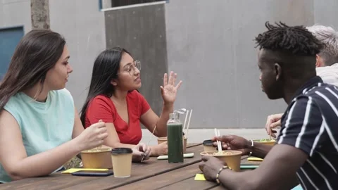 Multiracial friends having fun eating take away food outdoor in the city - Focus Stock Footage 160933379