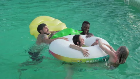 Multiracial friends playing and having fun in the pool with floats. Stock Footage 171938308