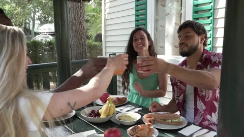 Multiracial friends toasting with juice while having breakfast on the terrace Stock Footage 171939359