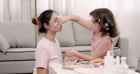 Multiracial girl using tissue to wipe makeup from Asian woman’s face while Video stock 334909432
