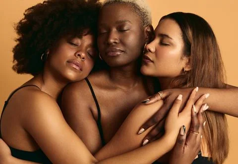 Multiracial girlfriends cuddling in studio Stock Photos
