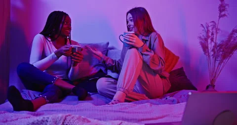 Multiracial girlfriends have fun dinner on the bed in neon light. Girls students Video stock 171287881