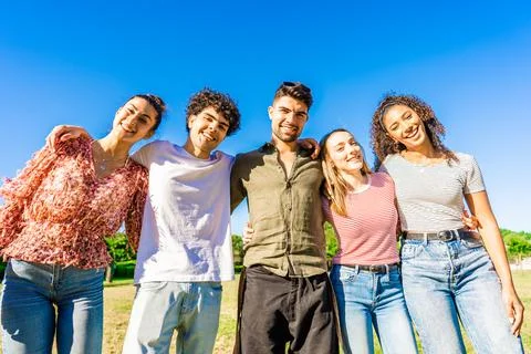 Multiracial group of college students embracing each other with arms around s Stock Photos