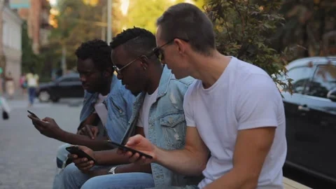 A multiracial group of friends on a bench talking and looking at the phone Stock Footage 141107928