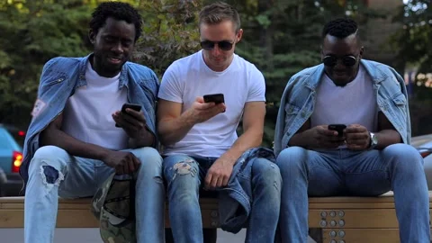 A multiracial group of friends on a bench talking and looking at the phone Stock Footage 141108154