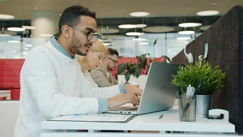 Multiracial group of people using laptops then talking in shared workspace Stock Footage 130861051