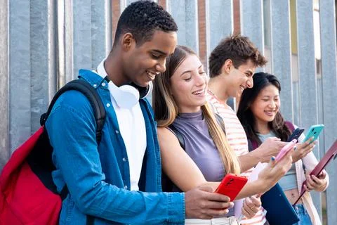 Multiracial Group Of Smiling Students Browsing Smartphone App Outdoors. Stock-Fotos