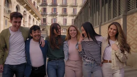 Multiracial group of smiling young gen z friends walking hugging on street in Stock Footage 256845263