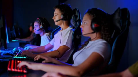 Multiracial group of teens in headsets playing video games in video game club Stock-Footage 250355308