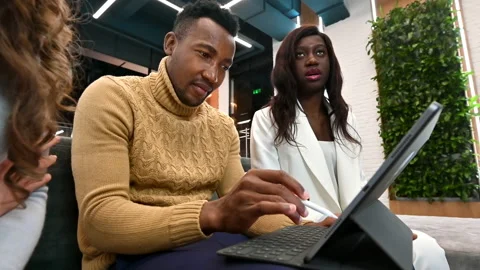 Multiracial group of workers in an office discussing business while using a Stock Footage 235262296