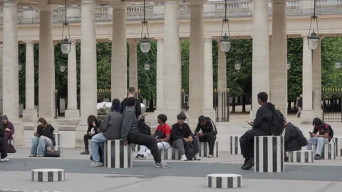 Multiracial group of young people sits on striped columns using smartphones Stock Footage 336722343