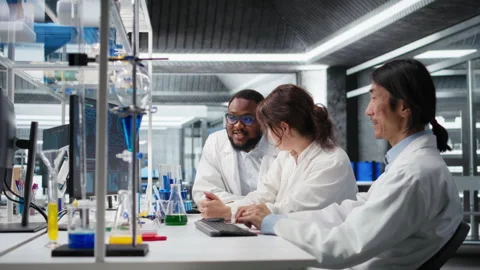 Multiracial lab technicians at PC desk looking at 3D molecular model Stock Footage 320146363