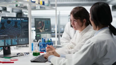 Multiracial lab technicians at PC desk looking at 3D molecular model Stock Footage 320726994