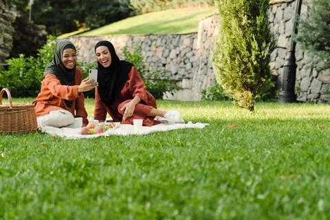 Multiracial muslim women taking selfie photo on cellphone during picnic Stock Photos