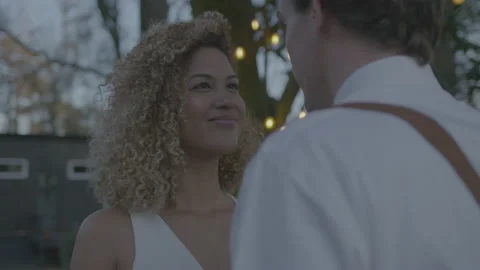 Multiracial Newlyweds in Backyard with String Lights Staring at Each Other Stock Footage 208784361