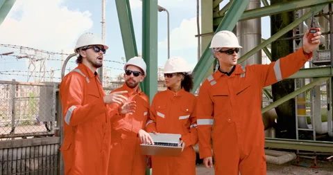 Multiracial refinery team discusses laptop data under pipe rack, planning safety Stock Footage 339648778
