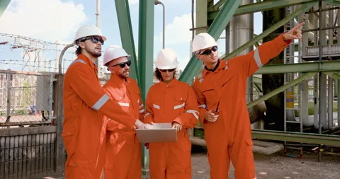 Multiracial refinery team listens while male supervisor points to unit, guiding Stock Footage 334833475