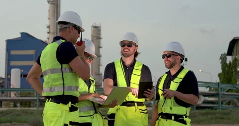 Multiracial refinery workforce reviews laptop and tablet while technician uses Stock Footage 337392875