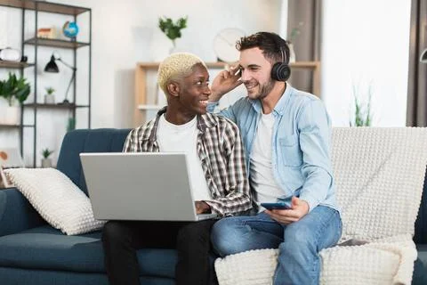 Multiracial same sex couple using gadgets at home 写真素材