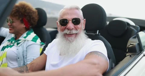 Multiracial senior couple having fun inside convertible car in summer vacation Stock Footage 153403458