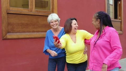 Multiracial senior friends using mobile phone having fun outdoor - Elderly Video stock 164677931