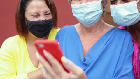 Multiracial senior friends using mobile phone having fun outdoor wearing safety Stock Footage 164678022