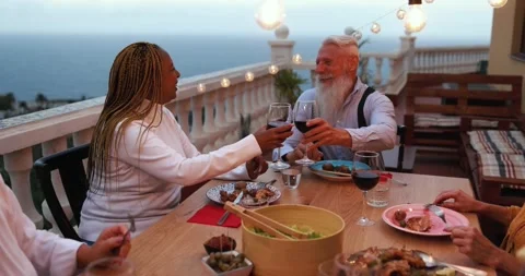 Multiracial senior people having fun at patio dinner cheering with wine Stock Footage 141122765