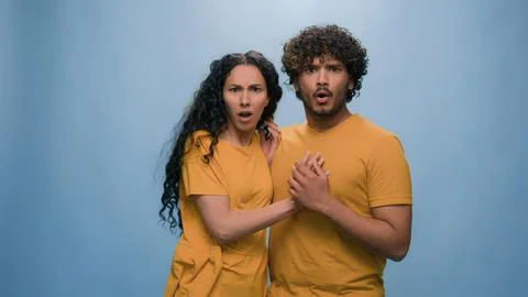 Multiracial shocked scared afraid couple amazed shocked Hispanic woman hiding Stock Photos