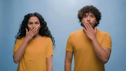Multiracial shocked scared afraid couple amazed shocked Hispanic woman hiding Stock Photos