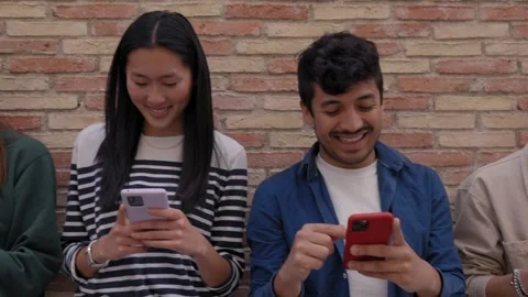 Multiracial smiling group young generation z on brick wall using phones together Stock Footage 247963425