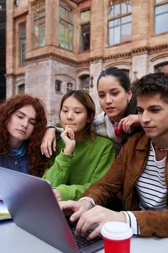 Multiracial students gathered together studying at university campus using a Stock Photos