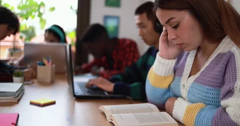 Multiracial students reading books and using laptop while studying together Stockbeeldmateriaal 164377833
