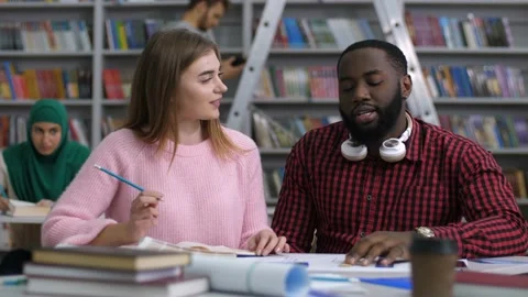Multiracial students studying together in library Video stock 101996488