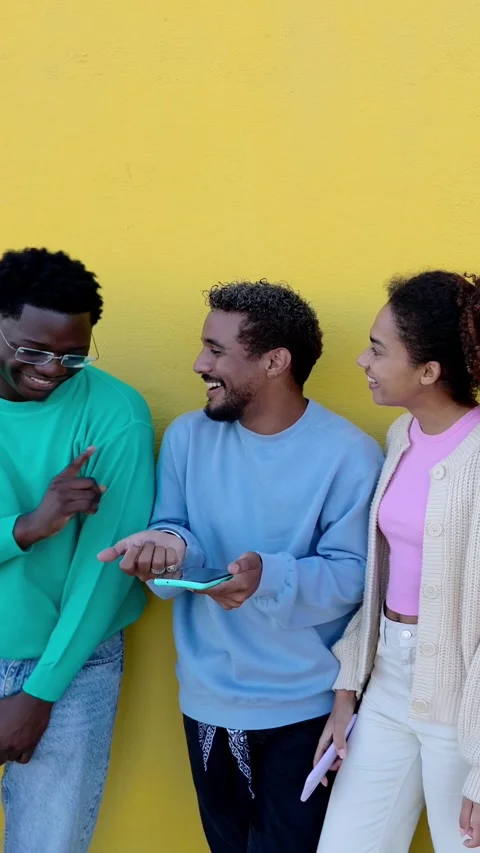 Multiracial students using mobile phones standing together over yellow wall. Stock Footage 312198503