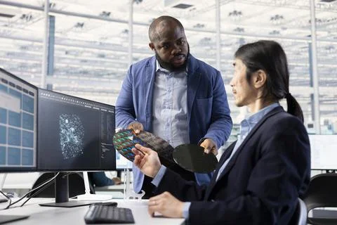 Multiracial technicians using AI to inspect silicon wafer substrates Stock Photos