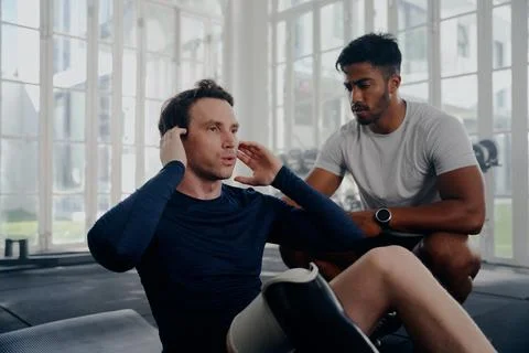 Multiracial trainer next to young man in sportswear with artificial limb doing Stock Photos