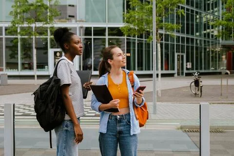 Multiracial women using cellphone while standing at city street Stock Photos