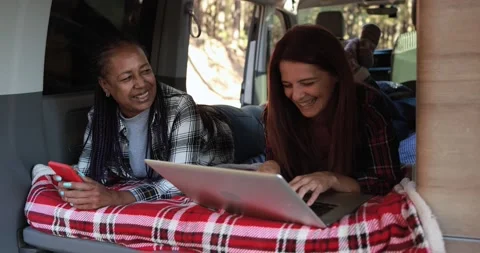 Multiracial women using computer laptop and mobile phone inside mini van camper Video stock 160538054