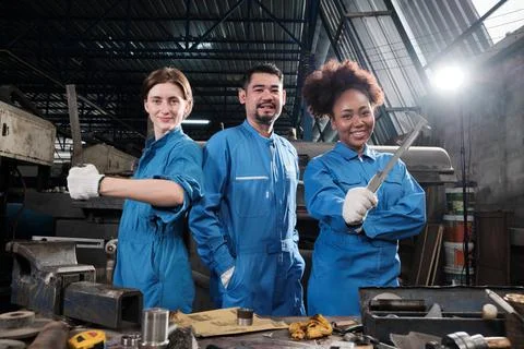 Multiracial workers collaborate and express happy work in a mechanical factor Stock Photos