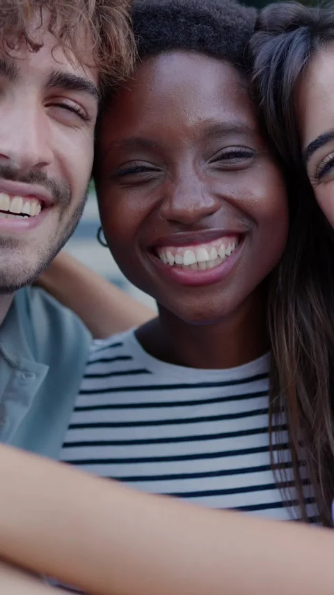 Multiracial young friends laughing while hugging each other sitting outdoors. Stock Footage 310778776