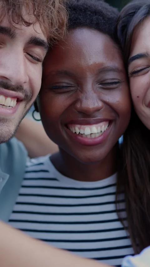 Multiracial young friends laughing while hugging each other sitting outdoors. Stock Footage 310778951