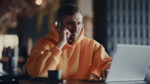 Multitasking Businessman Talking By Mobile Phone And Typing On Laptop In Cafe Stock Footage 343669397