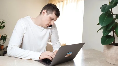 Multitasking. Engaged in online work, a young businessman using a laptop 動画素材 126104589