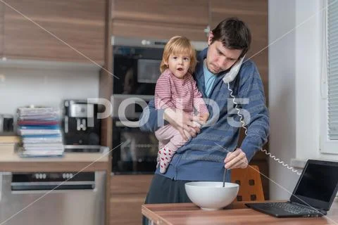 Multitasking father is babysitting and working at home. Stock Photos