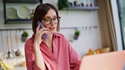 Multitasking freelancer ending call smartphone looking laptop at kitchen closeup Stock Footage 335104722