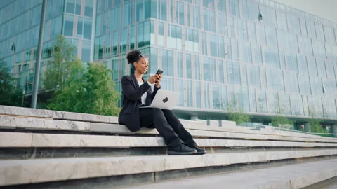 Multitasking freelancer lady working with laptop and calling by mobile in street Video stock 344391305