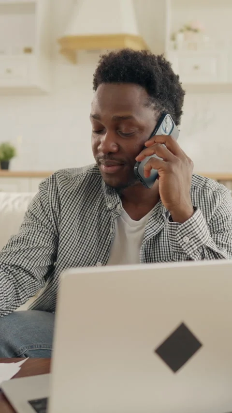 Multitasking male freelancer talking by phone and working with laptop at home Stock Footage 323581407
