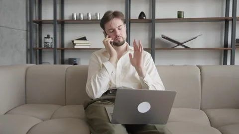 Multitasking Man On Call Gesturing While Working From Home With Laptop Stockbeeldmateriaal 304581237