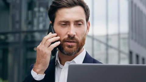 Multitasking man manager consultant talks on phone consulting client checks 写真素材