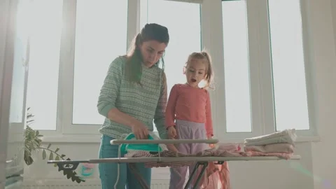 Multitasking Mom Ironing with Her Little One Stock Footage 254984717